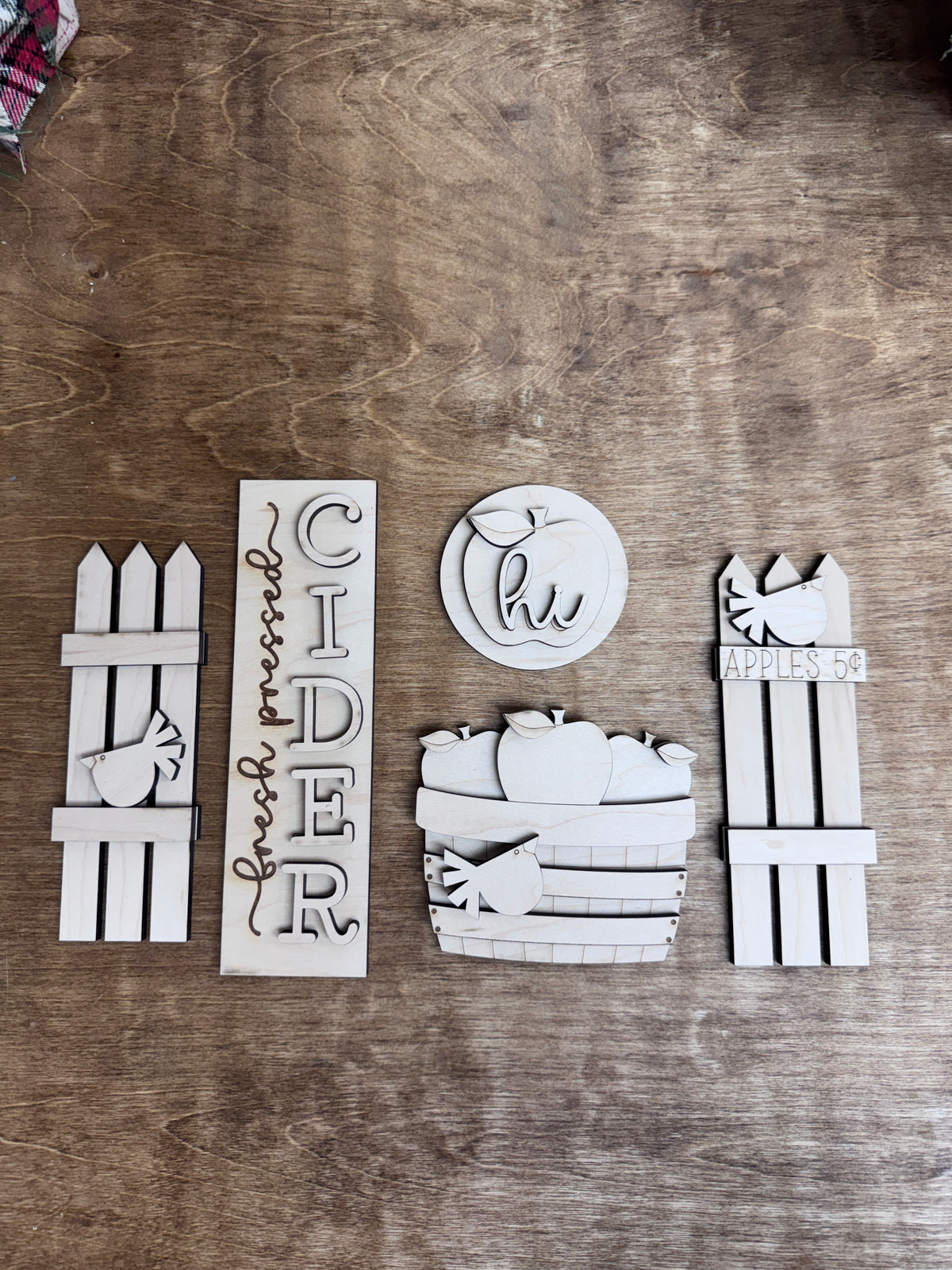 Flat lay of unfinished apple cider fall door insert kit with five decorative wooden components