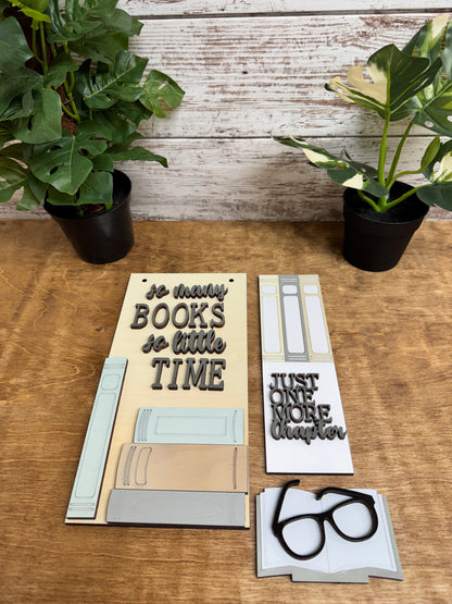 Three coordinating painted book lover post insert designs arranged together on a wooden table.