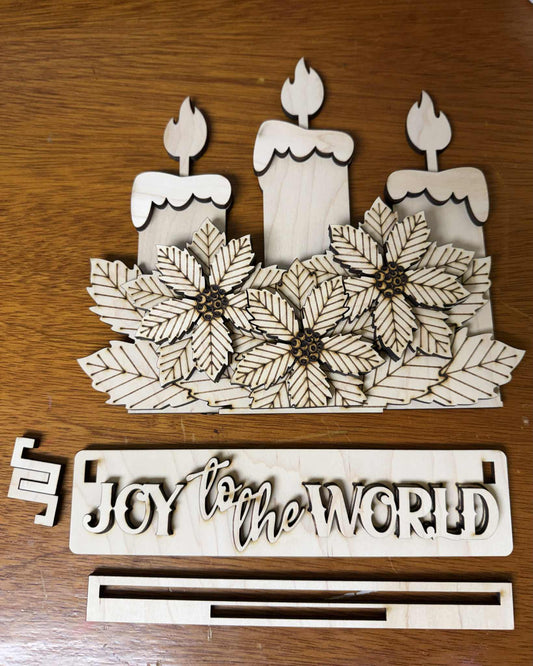 Wooden decorative piece with candles and 'Joy to the World' text on a wooden surface