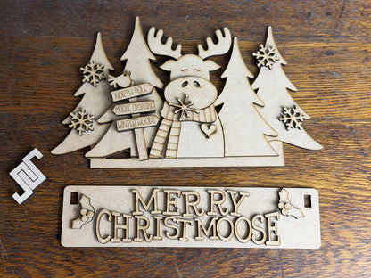 Merry Christmoose DIY Craft Kit featuring unpainted moose scene, Christmas trees, snowflakes, and festive sign.