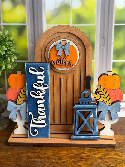 Interchangeable fall door display decorated with pumpkin topiaries, Thankful sign, lantern and Gather insert