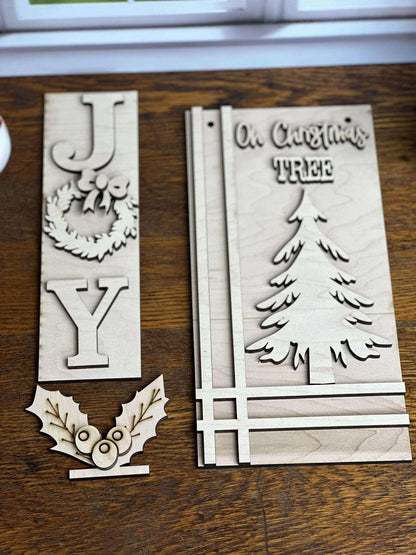 Close-up of unfinished wooden JOY wreath insert, Oh Christmas Tree hanging sign and holly leaves with berries for an interchangeable post.