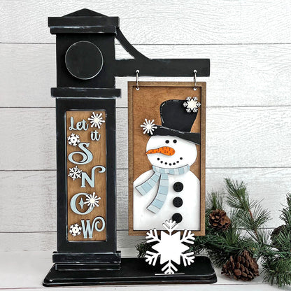 Let It Snow DIY winter craft kit featuring a snowman hanging sign, snowflake pop-out, and interchangeable post insert.