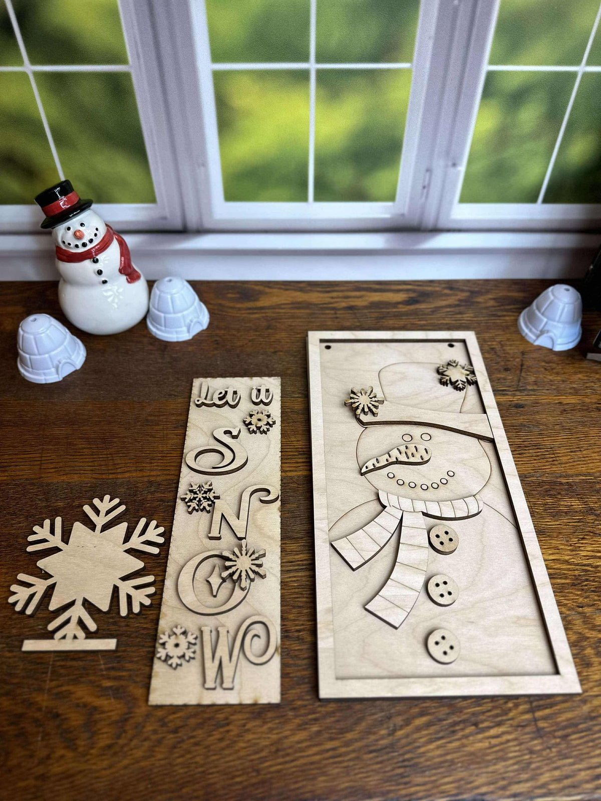 Unfinished Let It Snow DIY wooden craft kit showing the snowman hanging sign, vertical lettering insert and snowflake pop-out.